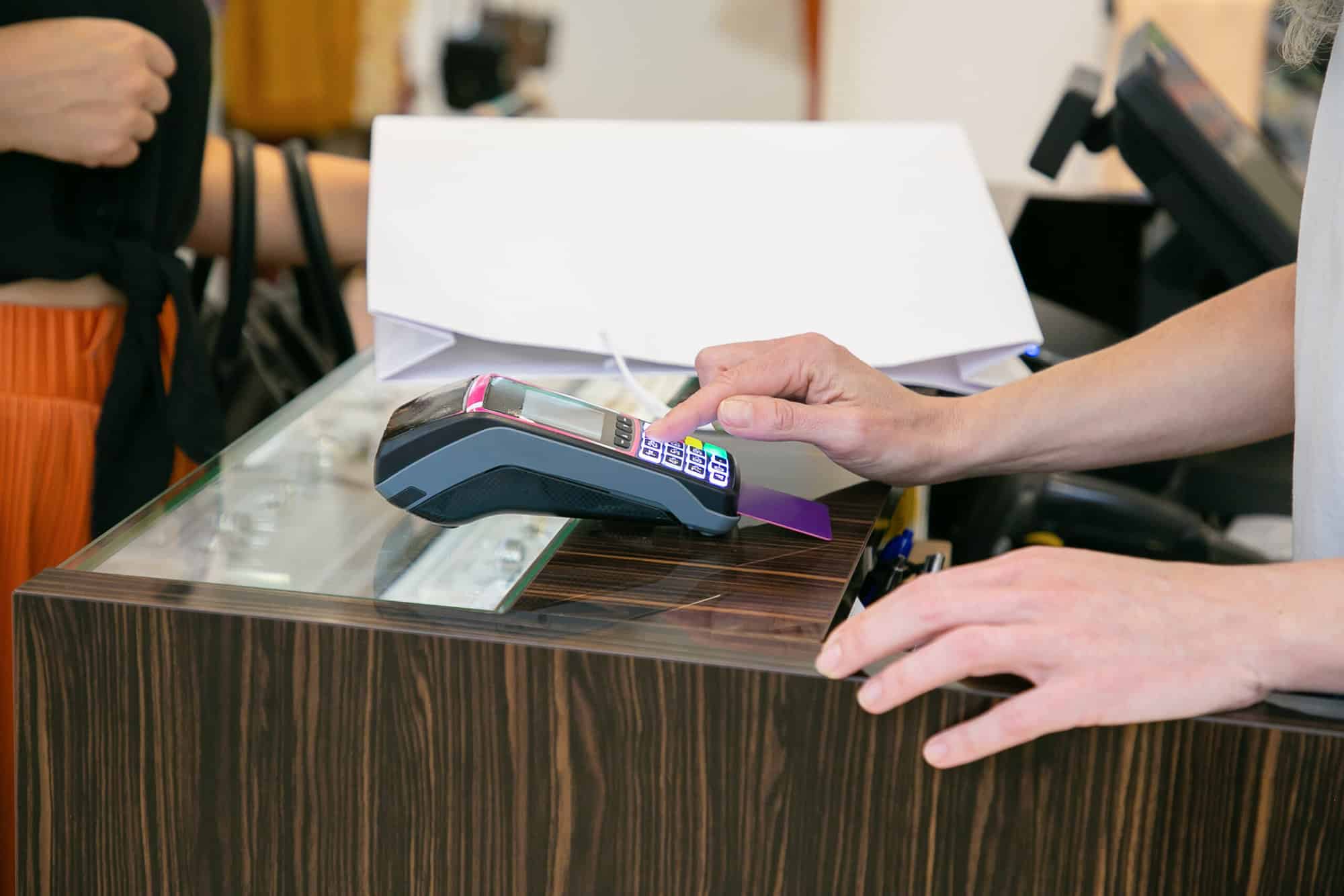 Shop cashier operating payment process with pos terminal